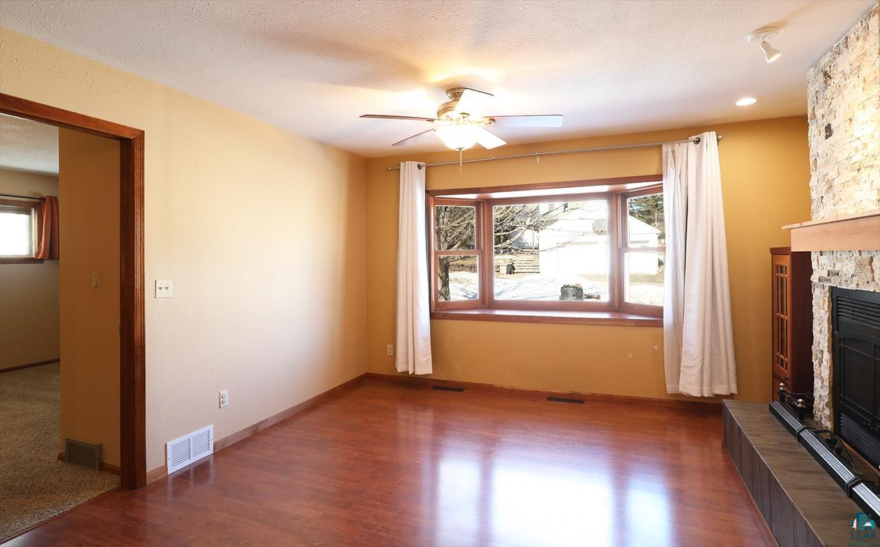 811 7th Street North Virginia, MN 55792 - Photo 16 of 37 Unfurnished living room featuring a fireplace, a ceiling fan, a textured ceiling, and wood finished floors