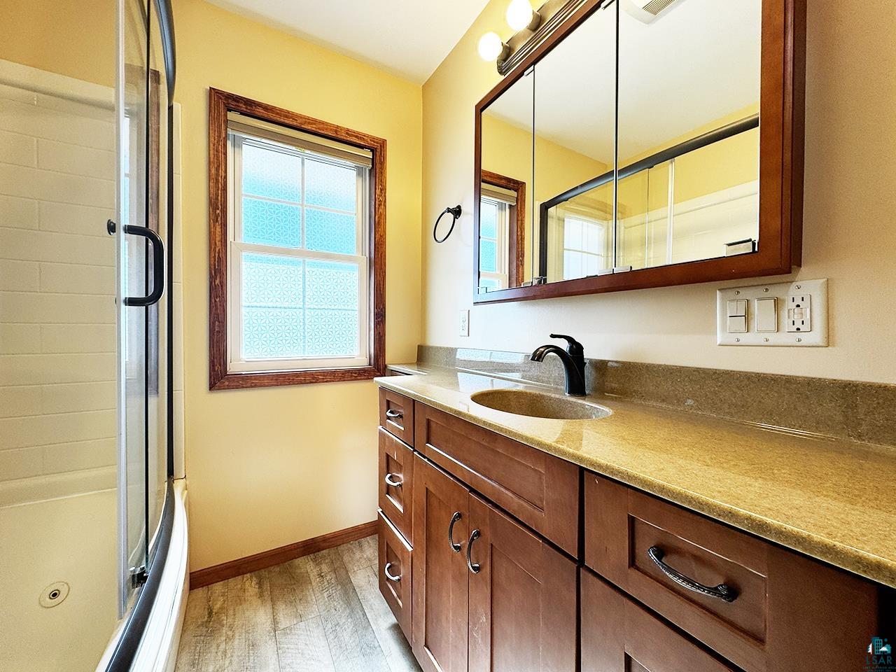 811 7th Street North Virginia, MN 55792 - Photo 18 of 37 Full bathroom featuring vanity, a combined bath / shower with jetted tub, and light wood-type flooring