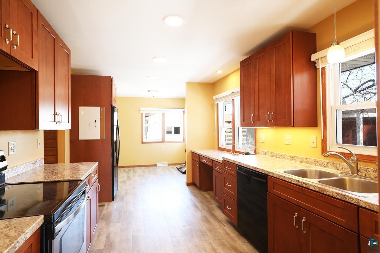 811 7th Street North Virginia, MN 55792 - Photo 5 of 37 Kitchen with electric stove, light countertops, dishwasher, light wood-style flooring, and freestanding refrigerator