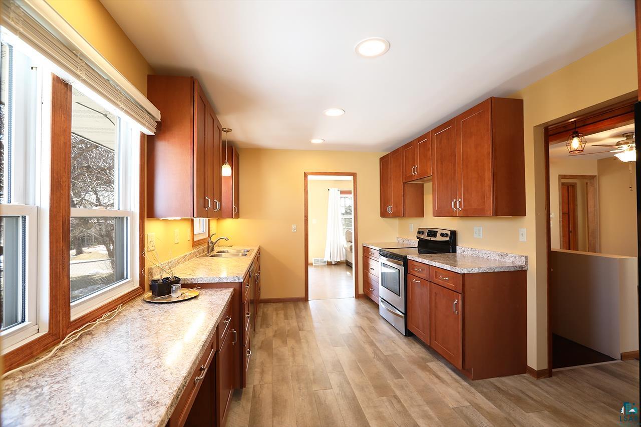 811 7th Street North Virginia, MN 55792 - Photo 6 of 37 Kitchen with stainless steel electric stove, light countertops, wood finish cabinets, light wood finished floors, and recessed lighting