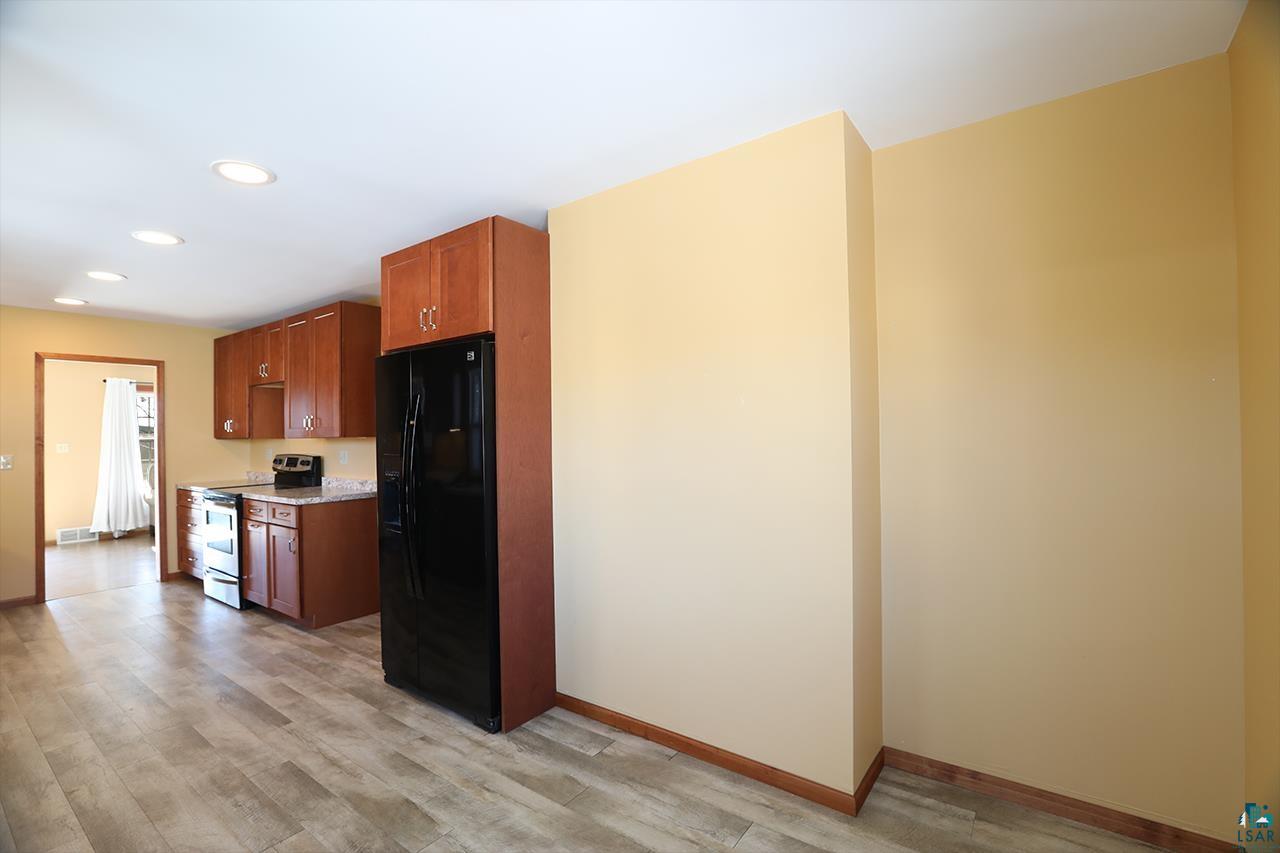 811 7th Street North Virginia, MN 55792 - Photo 7 of 37 Kitchen featuring black refrigerator with ice dispenser, stainless steel range with electric cooktop, light wood-type flooring, wood finish cabinets, and recessed lighting
