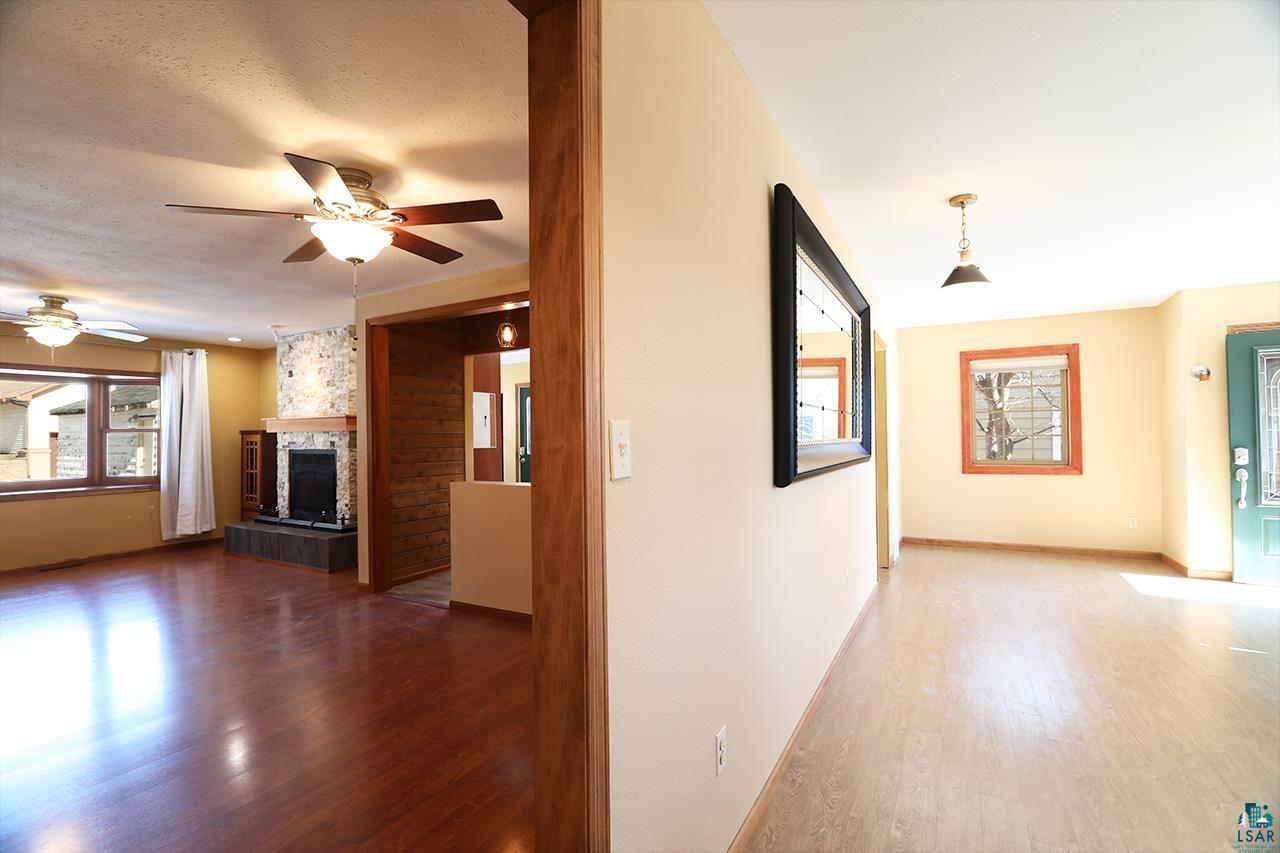 811 7th Street North Virginia, MN 55792 - Photo 10 of 37 Unfurnished living room with wood finished floors, a ceiling fan, and a tiled fireplace