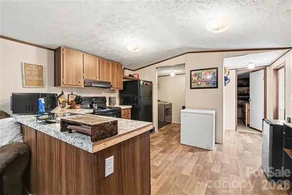 a kitchen with kitchen island a stove a refrigerator a sink dishwasher and wooden cabinets with wooden floor