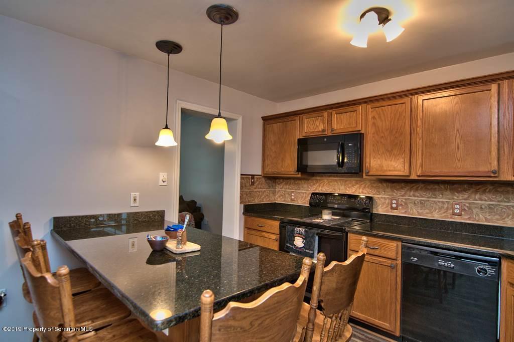 212 Summit Woods Road Moscow, PA 18444 - Photo 16 of 68 a kitchen with stainless steel appliances granite countertop a stove a sink a microwave a dining table and chairs with wooden floor