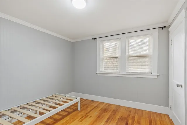 a view of a bedroom with wooden floor and a window