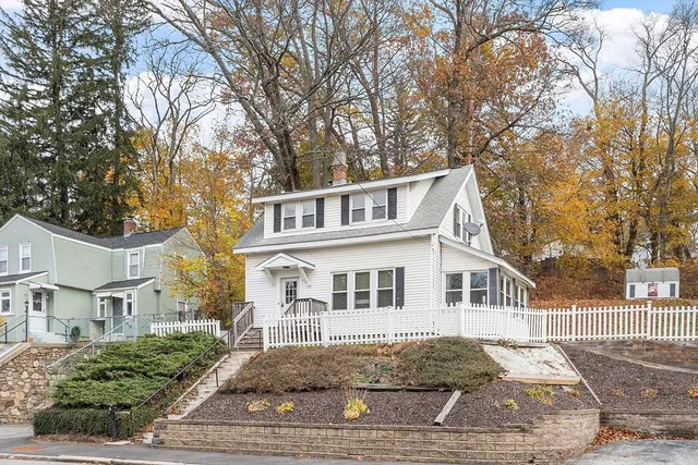 a view of a white house next to a yard with big trees