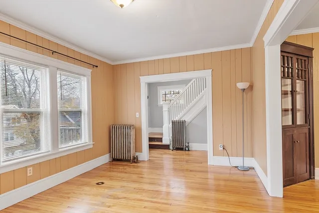 a view of an empty room with wooden floor and a window