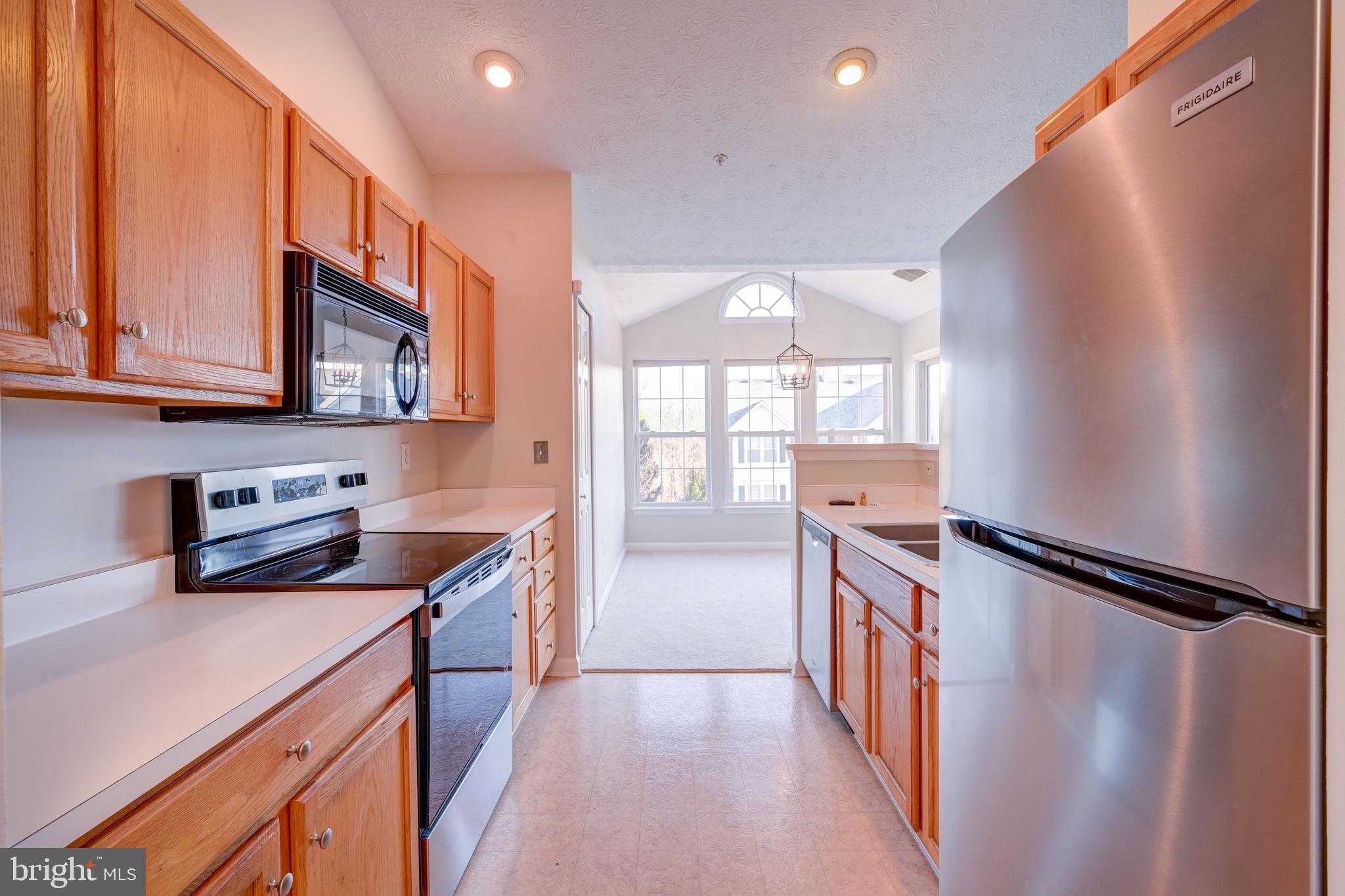 4933 Riders Court, Unit 4933 Owings Mills, MD 21117 - Photo 18 of 32 a kitchen with stainless steel appliances granite countertop a refrigerator a stove and a sink with wooden floor