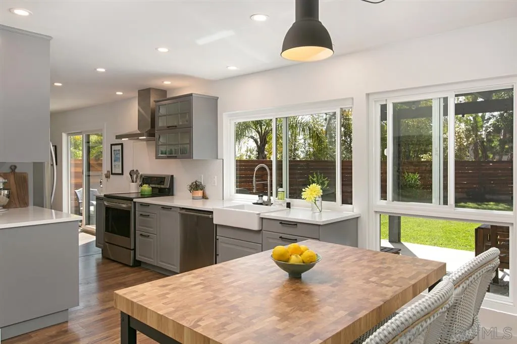 13637 Calais Drive Del Mar, CA 92014 - Photo 11 of 25 a kitchen with a stove a sink and a dining table with wooden floor