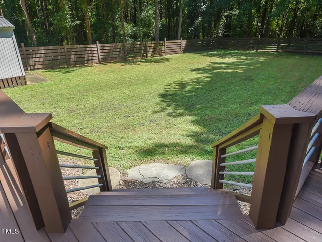 a view of a backyard with wooden fence and large trees
