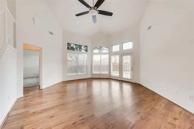 a view of an empty room with a window and wooden floor