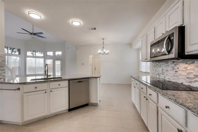 a large kitchen with stainless steel appliances granite countertop a sink and dishwasher a stove top oven with wooden floor