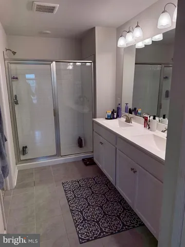 a bathroom with a double vanity sink a shower and a mirror