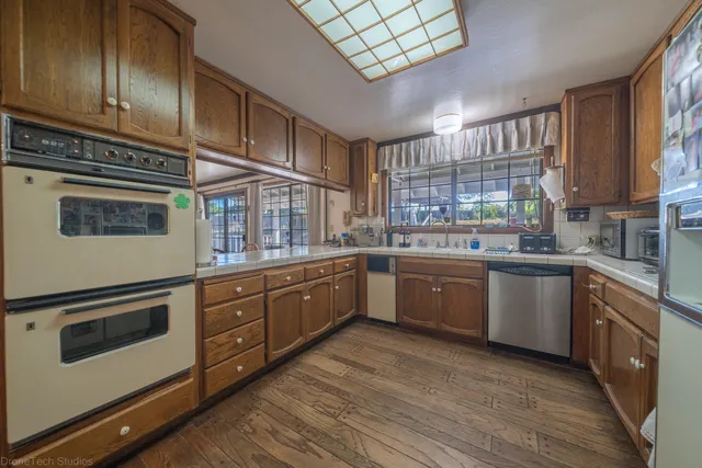 a kitchen with stainless steel appliances granite countertop a stove a sink dishwasher and a microwave oven with wooden floor