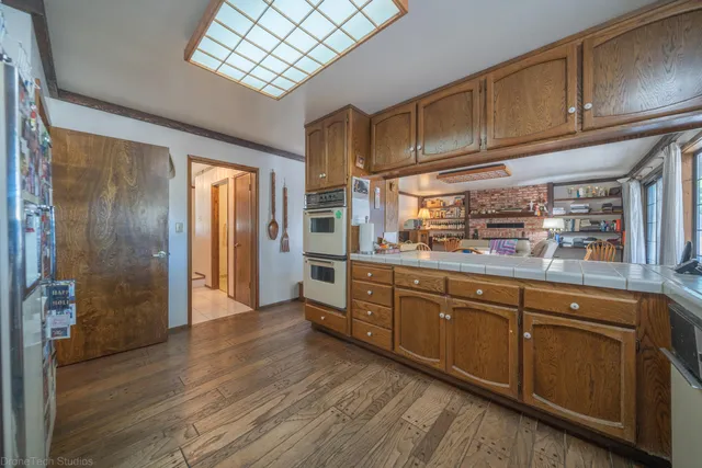 a kitchen with stainless steel appliances granite countertop a refrigerator a sink dishwasher and wooden cabinets with wooden floor