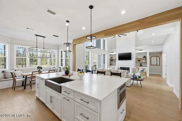 a large kitchen with kitchen island a large counter top appliances and a view of living room