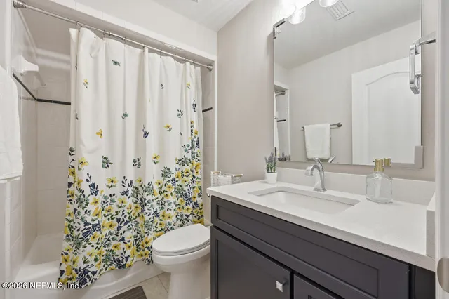 a bathroom with a sink a toilet a mirror and shower curtain