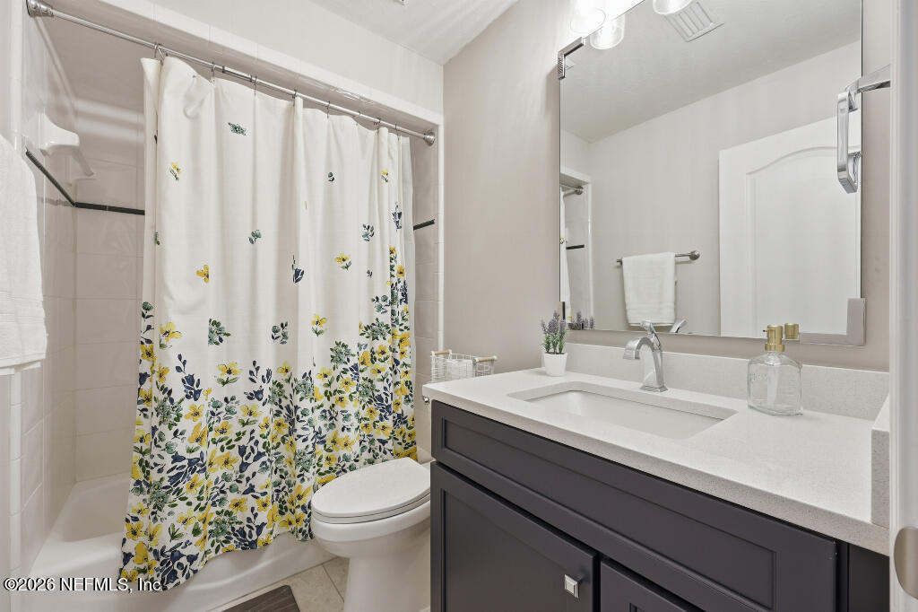 7956 Hollyridge Road Jacksonville, FL 32256 - Photo 33 of 50 a bathroom with a sink a toilet a mirror and shower curtain