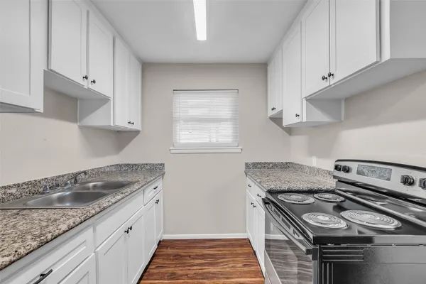 a kitchen with granite countertop a sink stove and cabinets