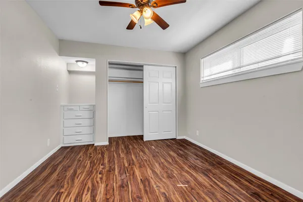 a view of empty room with wooden floor and fan