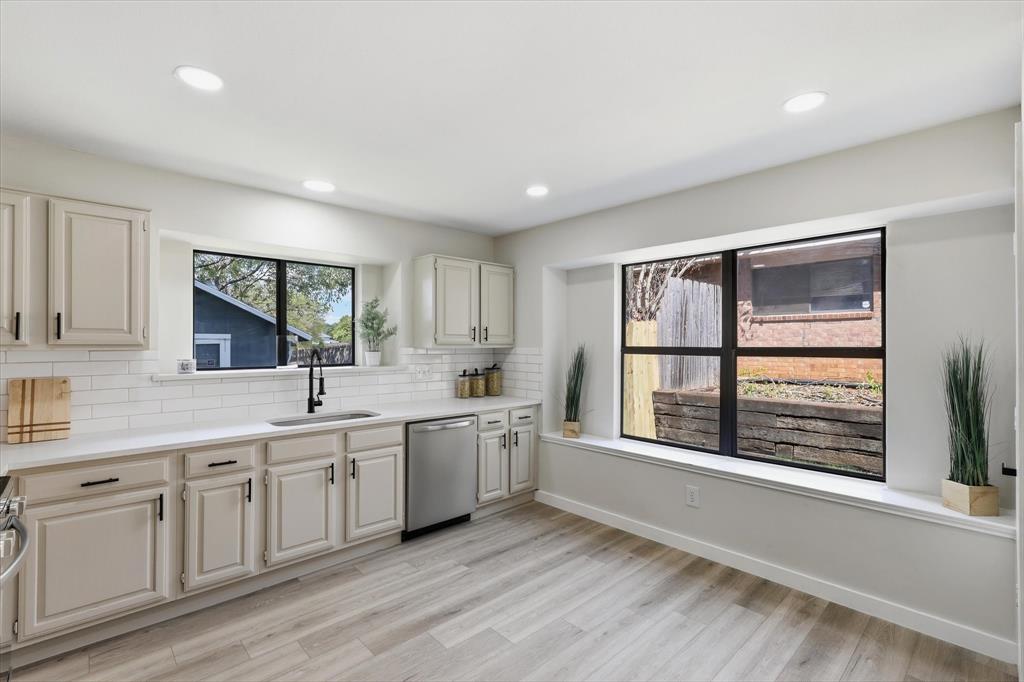 3405 Mill Ridge Street Bedford, TX 76021 - Photo 15 of 32 Recessed lighting illuminates the kitchen featuring light-toned cabinetry, a stainless steel dishwasher, white subway tile backsplash, and a large window above the sink