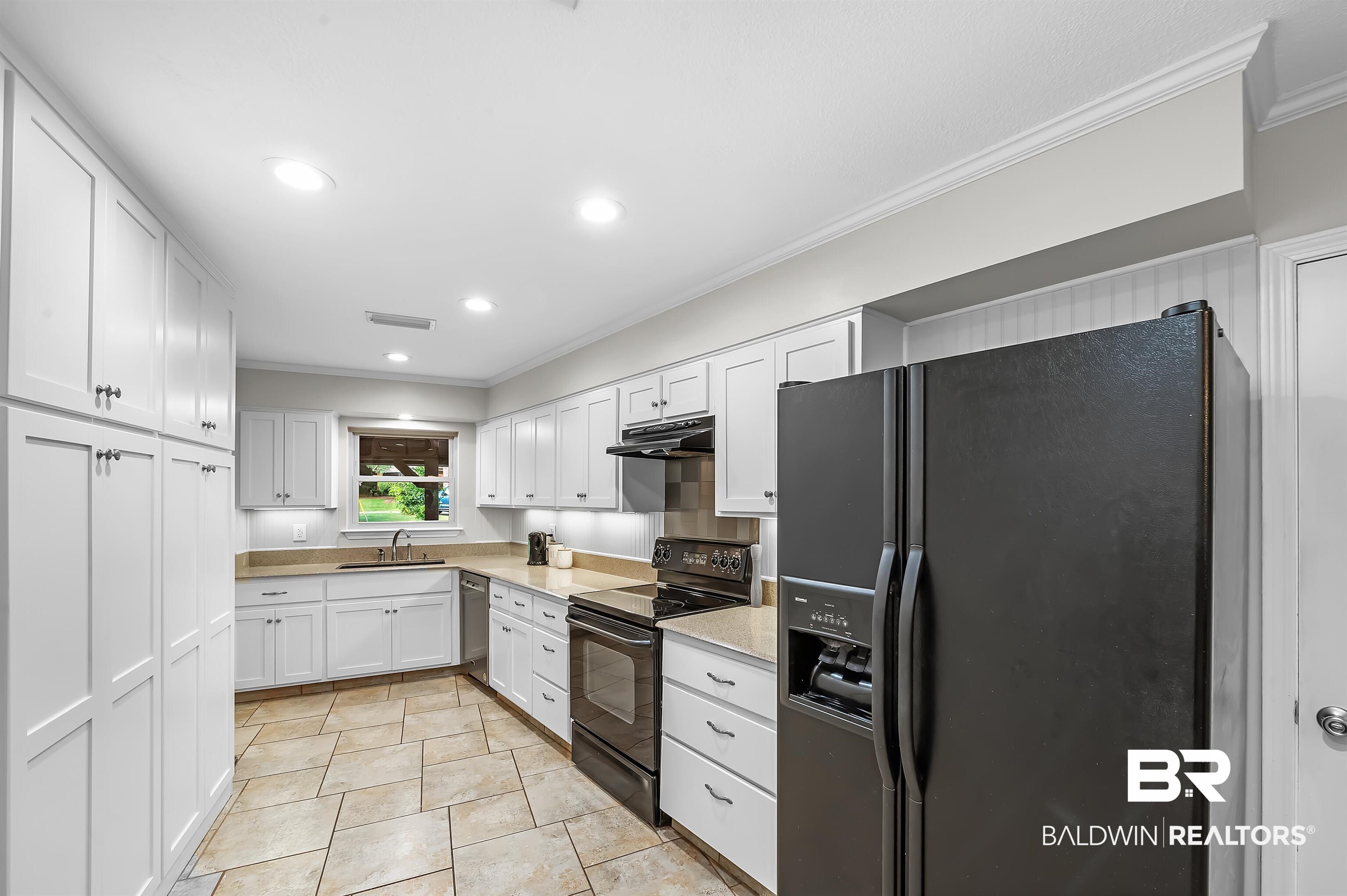104 James Circle Daphne, AL 36526 - Photo 22 of 62 Kitchen with white cabinetry, black appliances, crown molding, sink, and light tile patterned floors