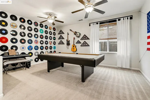 a room with pool table and ceiling fan