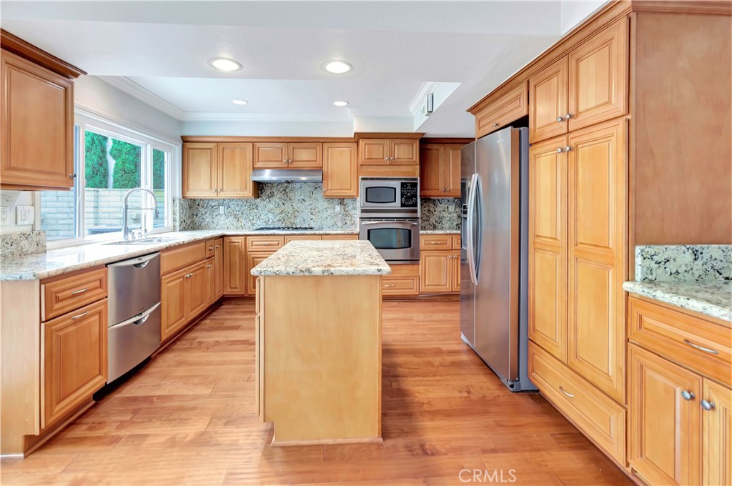4625 Green Tree Lane Irvine, CA 92612 - Photo 8 of 29 a kitchen with stainless steel appliances granite countertop a refrigerator a sink dishwasher and wooden cabinets with wooden floor