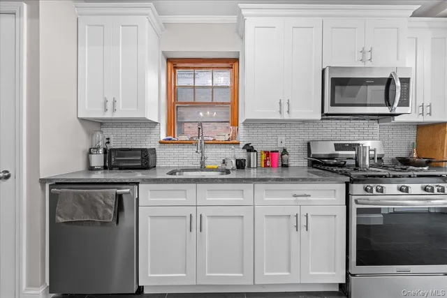a kitchen with white cabinets and appliances