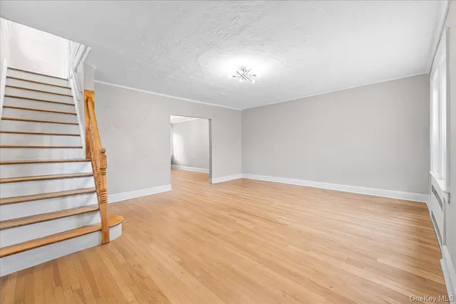 a view of an empty room with wooden floor and stairs