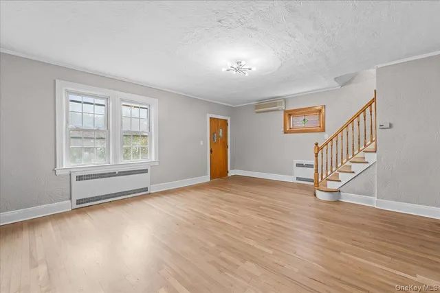 a view of an empty room with window and wooden floor