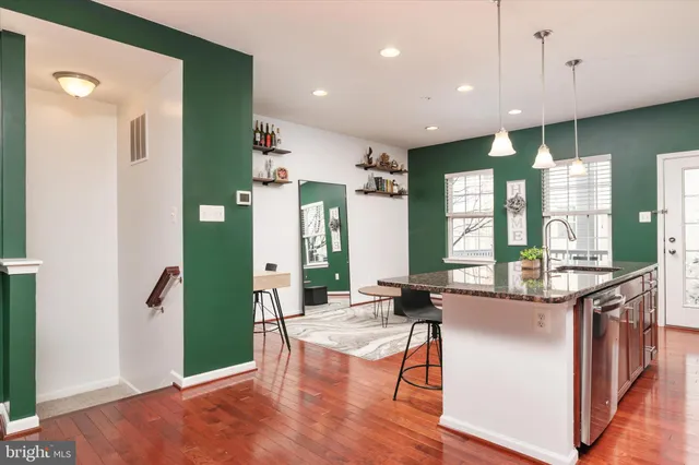 a kitchen with stainless steel appliances granite countertop a refrigerator a stove and a wooden floors