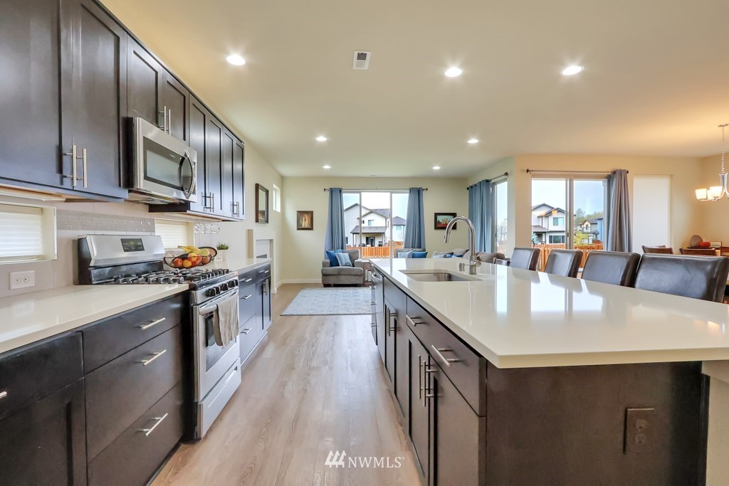471 Partlon Street Buckley, WA 98321 - Photo 6 of 23 a kitchen with stainless steel appliances granite countertop wooden floor a refrigerator a sink a stove a dining table and chairs