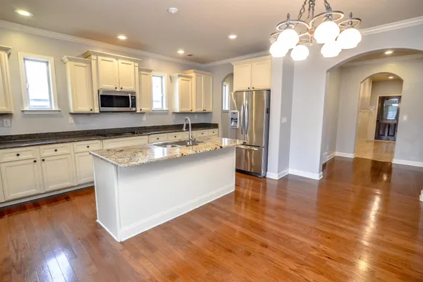 a large kitchen with stainless steel appliances granite countertop a stove and a wooden cabinets