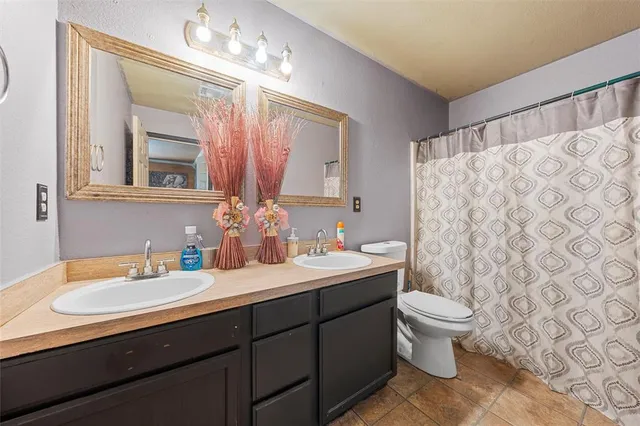 a bathroom with a double vanity sink mirror and toilet