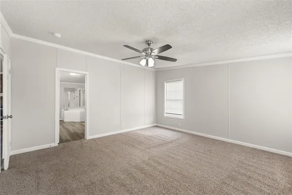an empty room with chandelier fan and windows