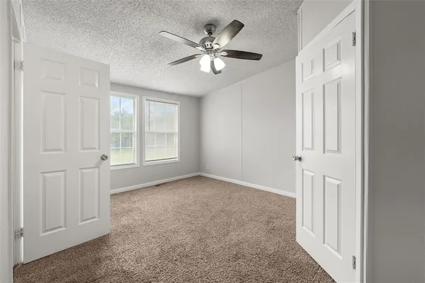 an empty room with windows and ceiling fan