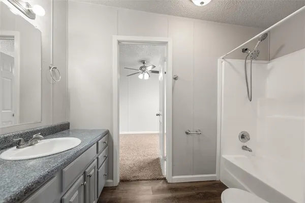 a bathroom with a granite countertop sink a toilet and shower