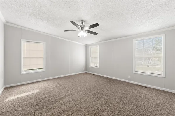 an empty room with windows and ceiling fan