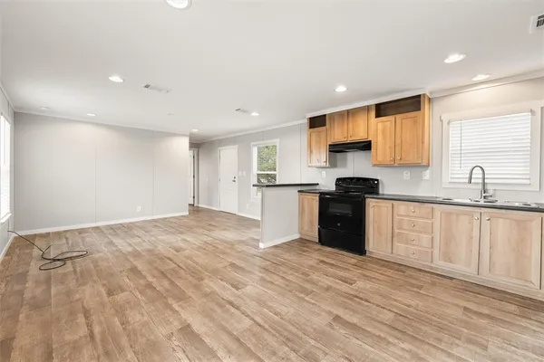a kitchen with granite countertop a stove a sink and a refrigerator