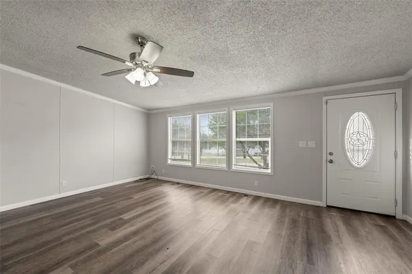 a view of an empty room with a window and wooden floor