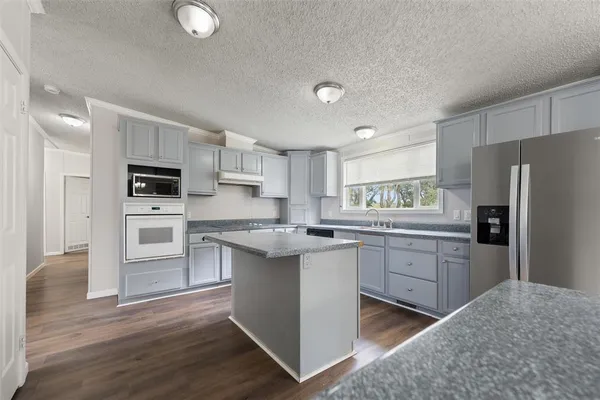 a kitchen with granite countertop a refrigerator stove and oven