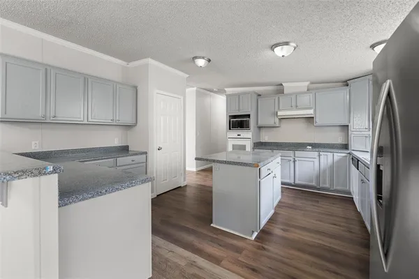 a kitchen with stainless steel appliances granite countertop a refrigerator sink and white cabinets