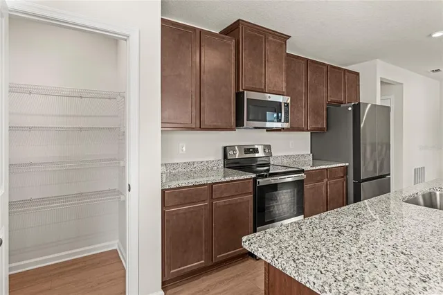 a kitchen with kitchen island granite countertop wooden cabinets and stainless steel appliances