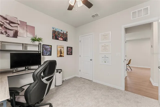 a view of a workspace with furniture and a ceiling fan