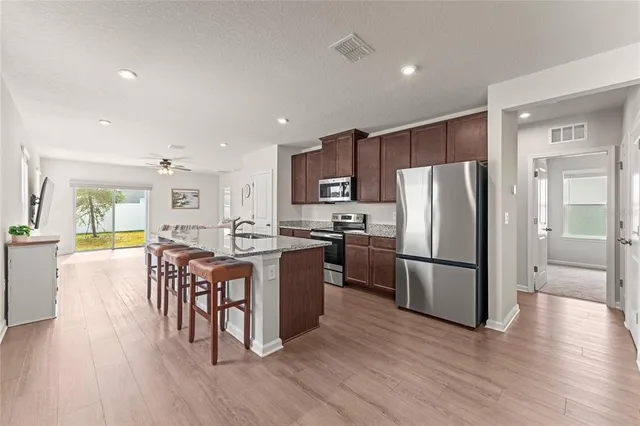 a kitchen with a refrigerator a stove top oven a sink dishwasher a dining table and chairs with wooden floor