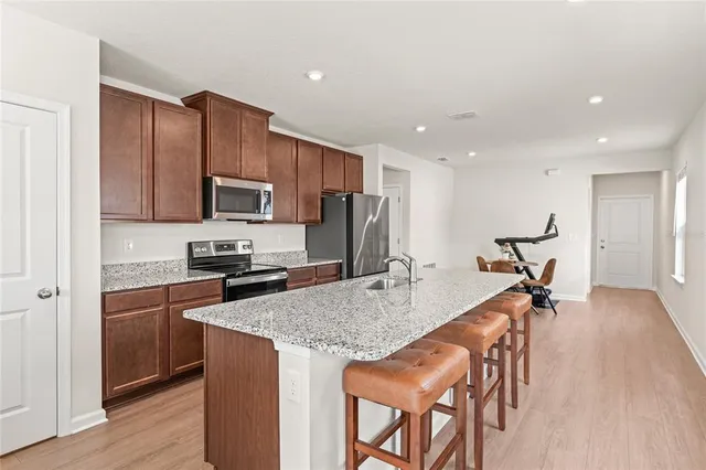 a kitchen with granite countertop kitchen island stainless steel appliances a stove a sink a refrigerator cabinets and wooden floor