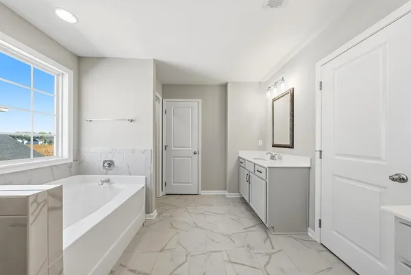 a spacious bathroom with a tub sink and mirror