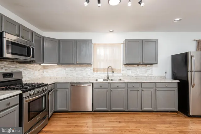 a kitchen with stainless steel appliances kitchen island granite countertop a sink stove and refrigerator