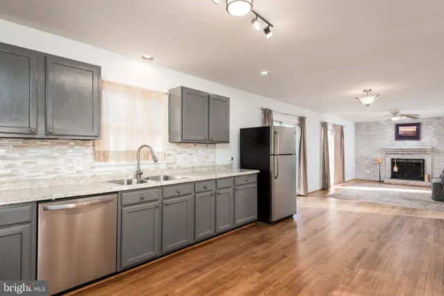 a kitchen with stainless steel appliances granite countertop a refrigerator a sink dishwasher a stove with wooden cabinets and floors